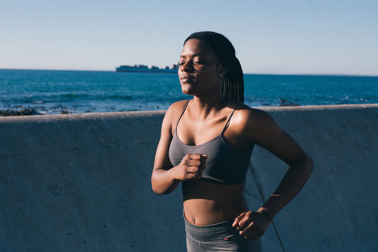 A young woman in activewear jogging along the ocean, embracing a healthy lifestyle.