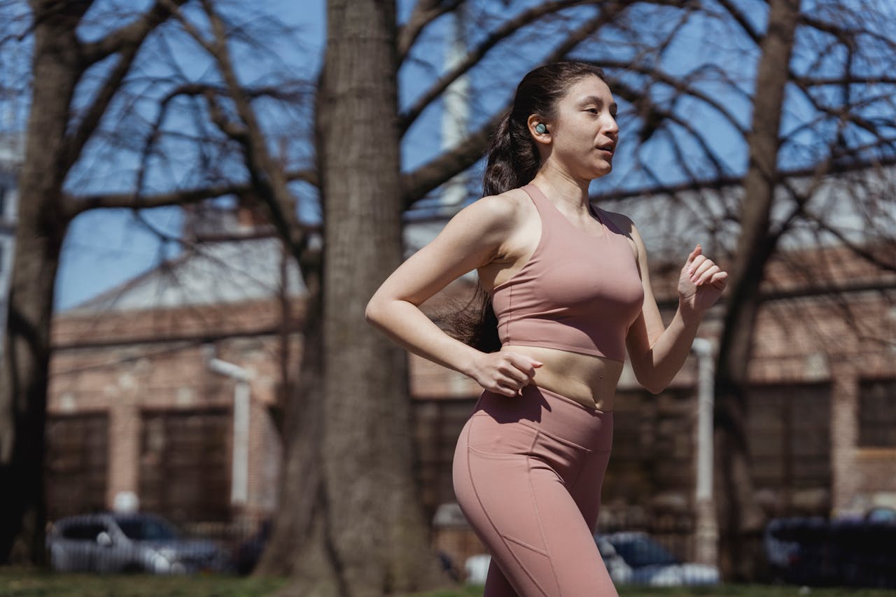Fit woman jogging in sportswear on a sunny day, embracing a healthy lifestyle.